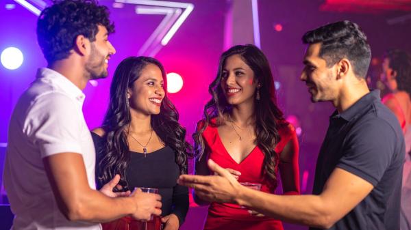 two couples having a conversation at a night club