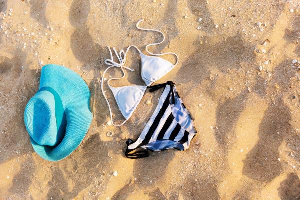 blue hat and a white and black striped bikini in the sand