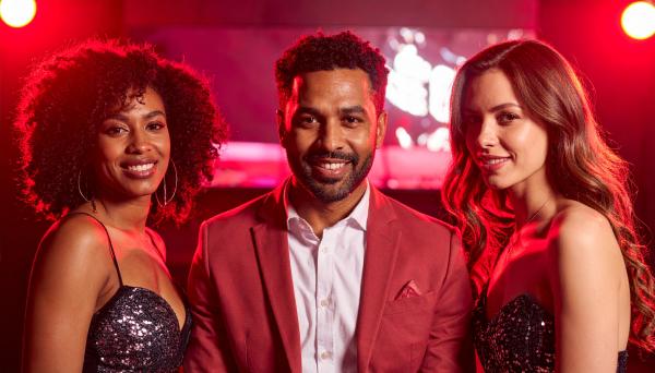 Man between two women in a nightclub with red lighting