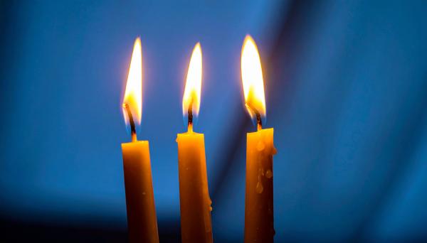 three candles in front of a dark background