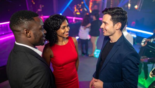 a couple having a conversation with a man at a night club