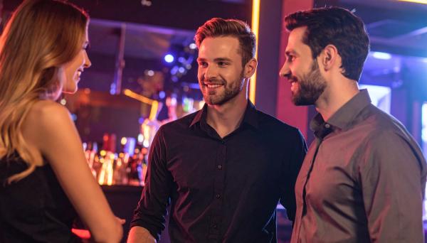two men and one woman having a conversation at a night club