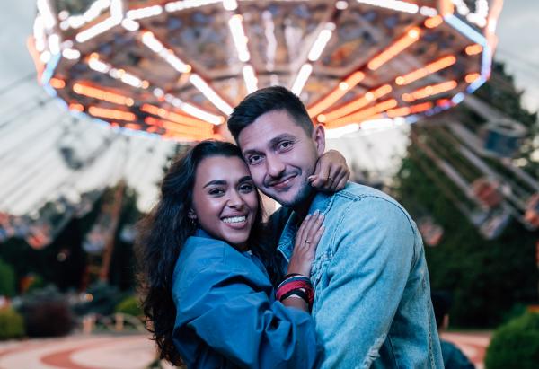 happy couple on a date at a summer festival in front of an illuminated swings ride