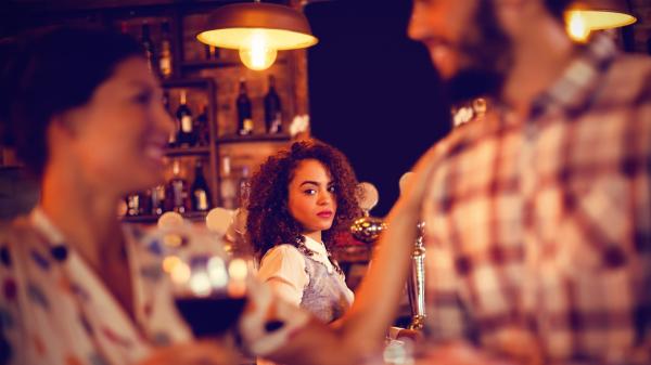 woman in focus looking forlornly at a blurred couple in the foreground