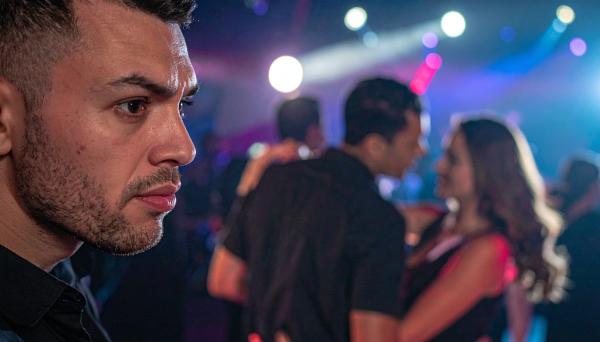 man in the foreground with a blurred couple dancing in the background