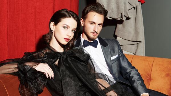 couple in dark evening formalwear on a plush sofa