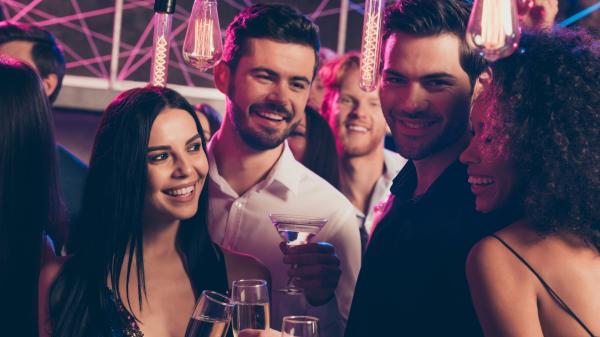 two happy couples toasting champagne at a night club