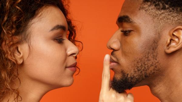 woman lovingly placing a finger over the lips of a man
