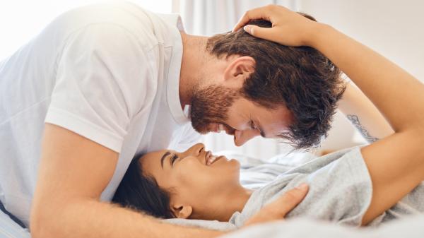 smiling couple in an intimate moment embracing on a bed