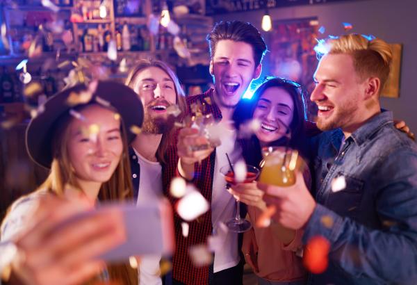 a group of men and women taking a selfie and having drinks at a club