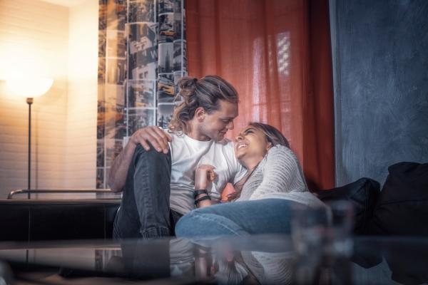 A couple sitting close together on a couch having an intimate conversation