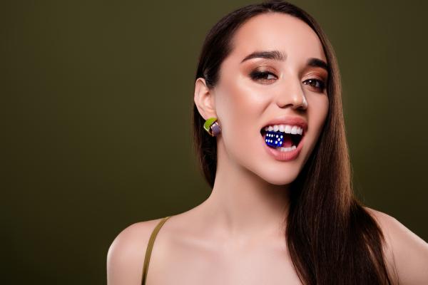 a woman in a dress, dice in mouth 