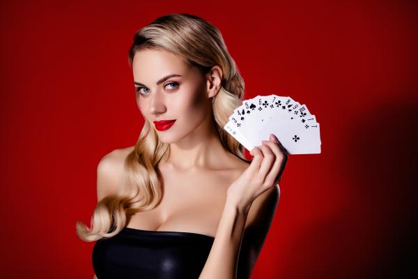 an attractive woman dressed in black holding playing cards
