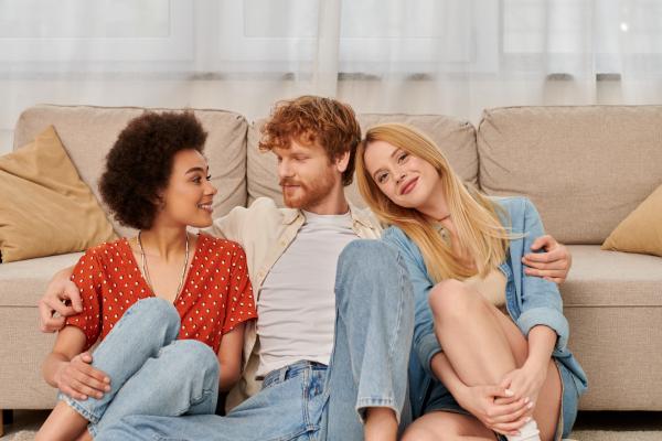 a man sitting in the middle of two women with an arm around each of them