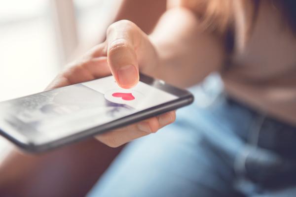 a womans hand on a phone showing a dating site