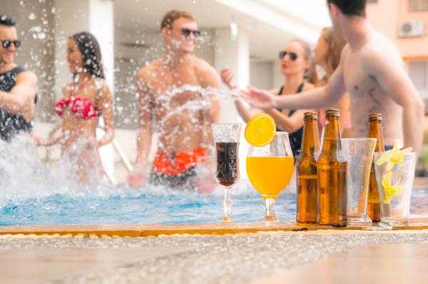 a group of people partying in a pool with some drinks in the foreground