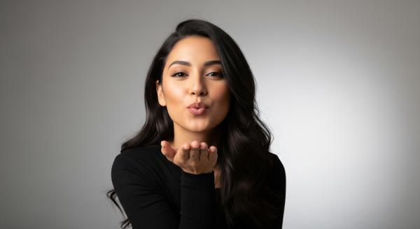 a brunette woman in a black shirt blowing a kiss