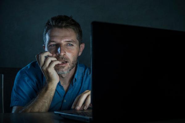 a man dressed in a blue shirt looking at something on a laptop