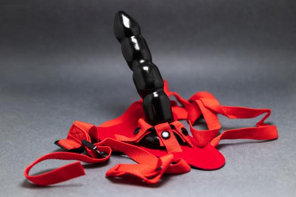 a black strap-on dildo with a red harness