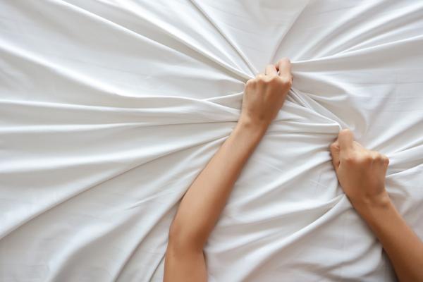 two hands gripping a bed sheet