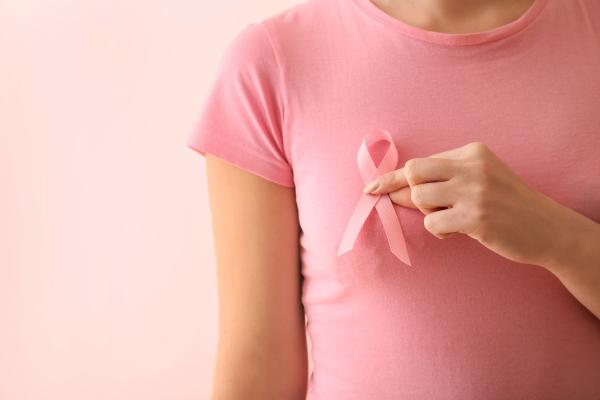 a woman wearing a pink shirt holding a pink ribbon to her chest
