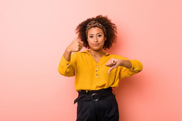 a woman wearing a yellow shirt holding one thumb up and one thumb now