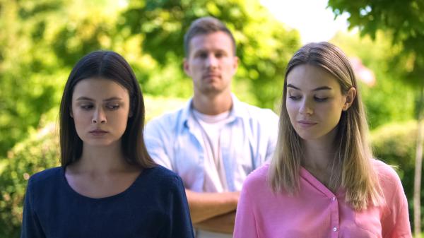a man standing behind two woman outdoors