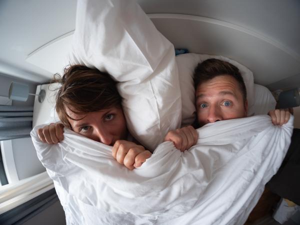 a man and women under blankets in bed with awkward expressions on their faces