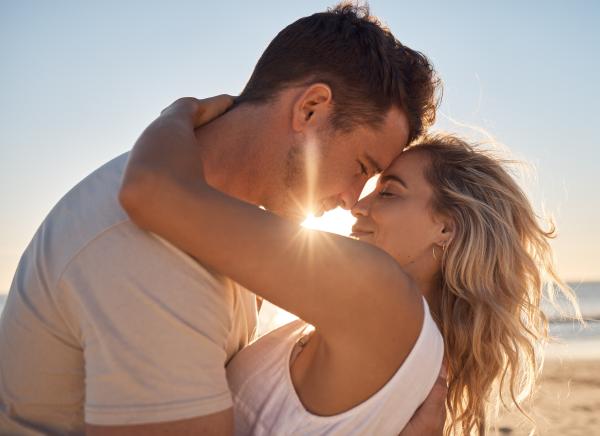 a man and woman dressed in white embracing on the beach