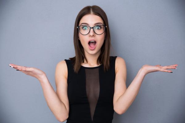 woman in black dress holding her hands up looking surprised