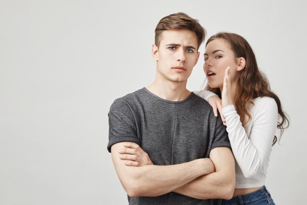 a woman wearing white whispering to a man with a serious look on his face
